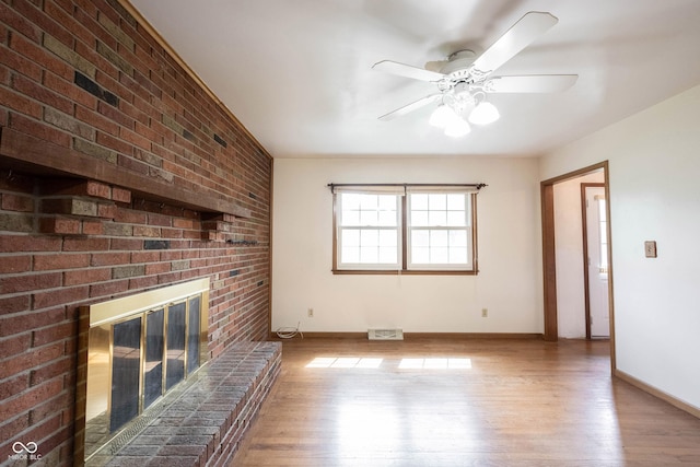10244 Washington Blvd, Carmel, IN 46280 - unfurnished living room with wood finished floors, a fireplace, a ceiling fan, baseboards, and brick wall