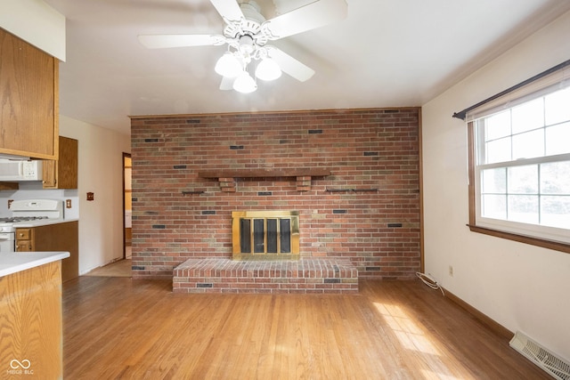 10244 Washington Blvd, Carmel, IN 46280 - unfurnished living room featuring light wood-type flooring, a ceiling fan, and a fireplace