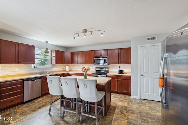 2509 Cedarmill Dr, Franklin, IN 46131 - kitchen with appliances with stainless steel finishes, tasteful backsplash, a kitchen breakfast bar, light countertops, and a kitchen island