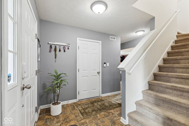 2509 Cedarmill Dr, Franklin, IN 46131 - entryway with stairway, a textured ceiling, stone finish flooring, and baseboards