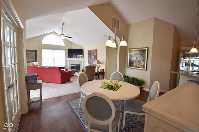 1150 Extraordinary Trl, Greenfield, IN 46140 - dining room with vaulted ceiling, a tiled fireplace, dark wood-style floors, ceiling fan, and baseboards