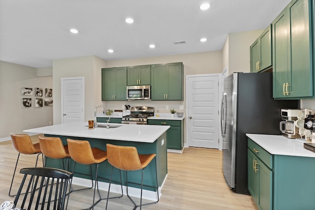 6917 Wolf Creek Ct, Whitestown, IN 46075 - kitchen featuring appliances with stainless steel finishes, green cabinets, a sink, light wood finished floors, and recessed lighting