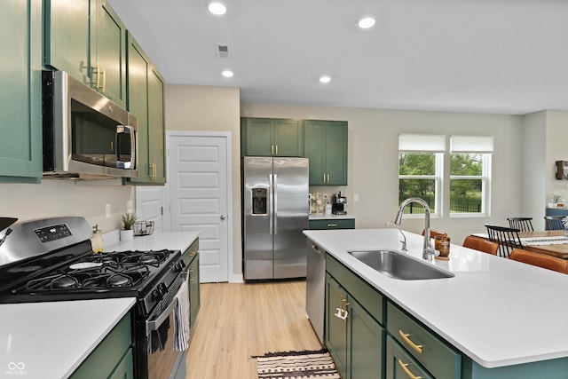 6917 Wolf Creek Ct, Whitestown, IN 46075 - kitchen with green cabinets, stainless steel appliances, a sink, light countertops, and light wood-style floors