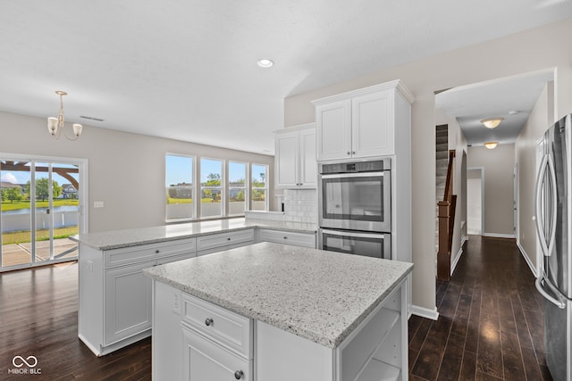 4539 Maldenhair Dr, Indianapolis, IN 46239 - kitchen with appliances with stainless steel finishes, a center island, a peninsula, dark wood-style flooring, and light stone counters
