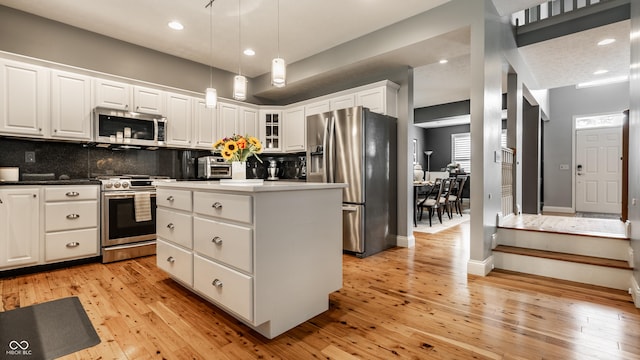 9804 Wentworth Ct, Carmel, IN 46032 - kitchen with stainless steel appliances, white cabinets, backsplash, light wood-style flooring, and a center island
