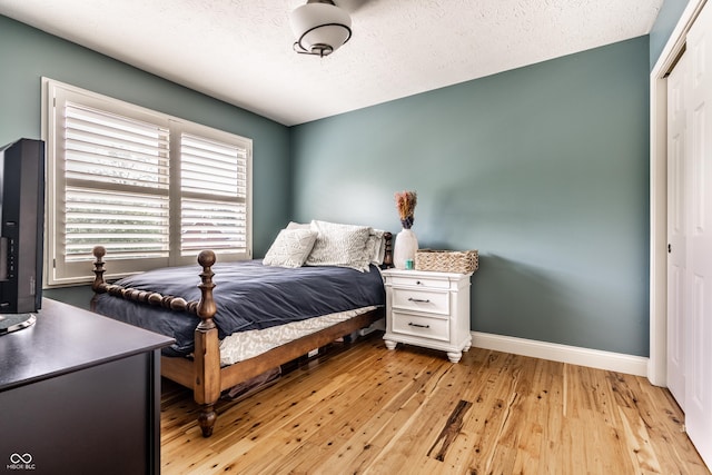 9804 Wentworth Ct, Carmel, IN 46032 - bedroom with a closet, light wood-style flooring, baseboards, and a textured ceiling