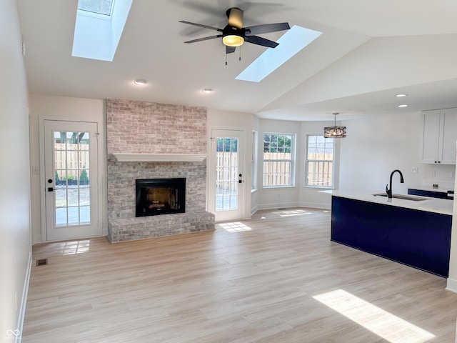 6845 Arjay Dr, Indianapolis, IN 46217 - unfurnished living room with a skylight, a sink, baseboards, a brick fireplace, and high vaulted ceiling