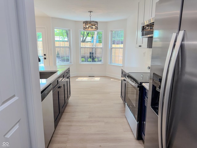 6845 Arjay Dr, Indianapolis, IN 46217 - kitchen featuring appliances with stainless steel finishes, light countertops, light wood finished floors, decorative light fixtures, and plenty of natural light