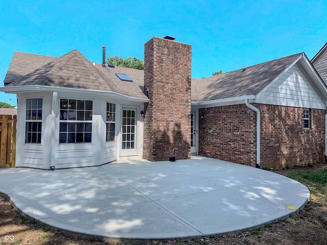 6845 Arjay Dr, Indianapolis, IN 46217 - rear view of house featuring roof with shingles, brick siding, a chimney, and a patio