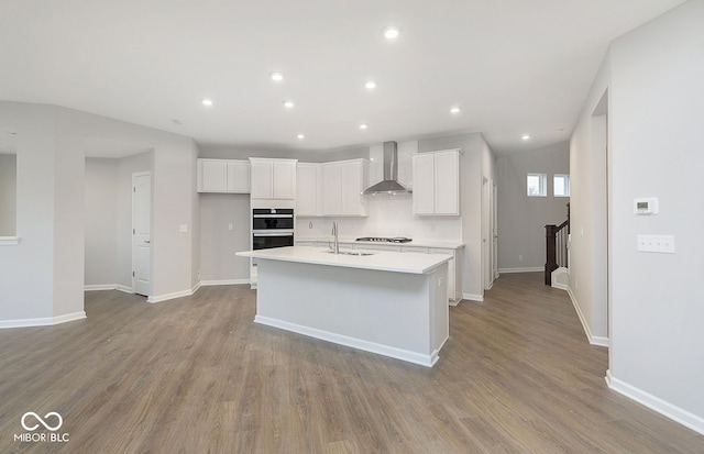 577 Dalton Way, Avon, IN 46123 - kitchen with wall chimney range hood, an island with sink, white cabinets, light countertops, and double oven