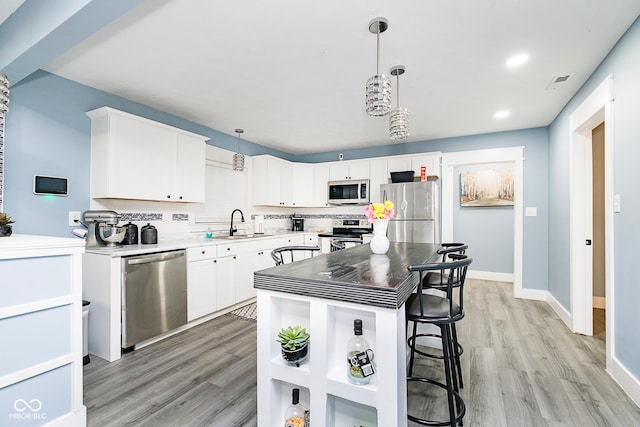 2209 W 9th St, Muncie, IN 47302 - kitchen featuring stainless steel appliances, light wood-type flooring, a sink, white cabinets, and decorative light fixtures
