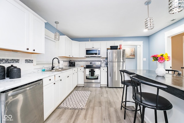 2209 W 9th St, Muncie, IN 47302 - kitchen with appliances with stainless steel finishes, a sink, light wood-style floors, and tasteful backsplash