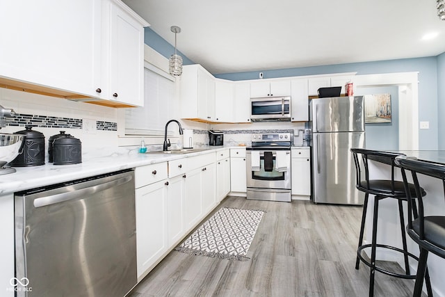 2209 W 9th St, Muncie, IN 47302 - kitchen with stainless steel appliances, a sink, light wood finished floors, backsplash, and white cabinets
