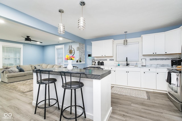 2209 W 9th St, Muncie, IN 47302 - kitchen featuring a sink, stainless steel electric stove, a center island, a kitchen bar, and light wood-style floors