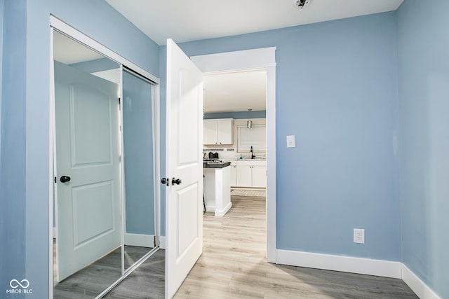 2209 W 9th St, Muncie, IN 47302 - corridor featuring a sink, light wood finished floors, and baseboards