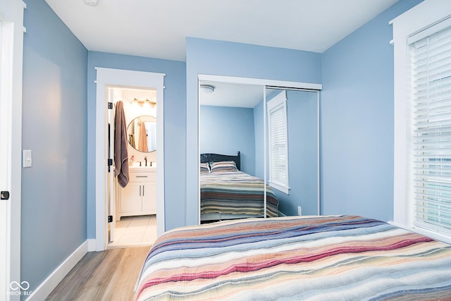 2209 W 9th St, Muncie, IN 47302 - bedroom with wood finished floors, baseboards, a closet, connected bathroom, and a sink