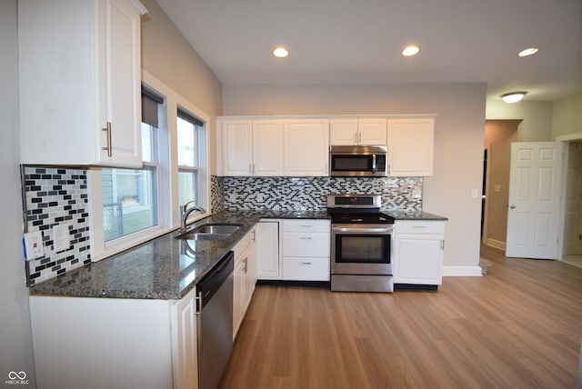4231 Carrollton Ave, Indianapolis, IN 46205 - kitchen featuring appliances with stainless steel finishes, a sink, light wood-style floors, white cabinets, and decorative backsplash