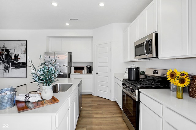 15387 Alperton Rd, Fishers, IN 46037 - kitchen with appliances with stainless steel finishes, wood finished floors, light countertops, white cabinets, and recessed lighting