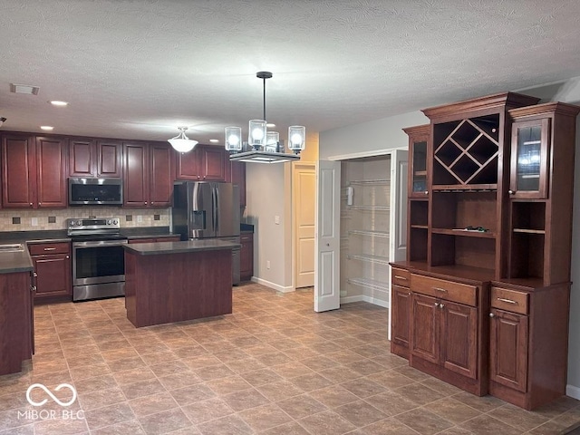 1287 Highland Lake Way, Brownsburg, IN 46112 - kitchen with appliances with stainless steel finishes, dark countertops, tasteful backsplash, a kitchen island, and a chandelier