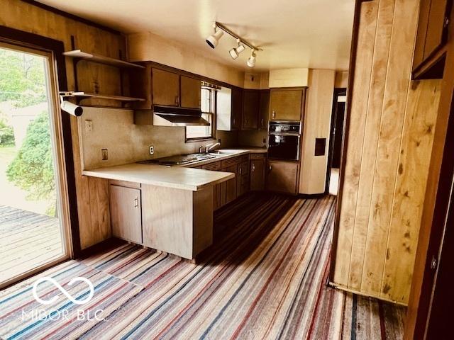 3824 Forest Ridge Dr, Fort Wayne, IN 46804 - kitchen with black oven, a peninsula, under cabinet range hood, light countertops, and a sink