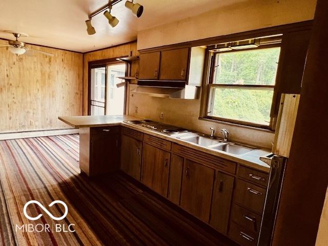 3824 Forest Ridge Dr, Fort Wayne, IN 46804 - kitchen with a sink, a peninsula, stainless steel gas cooktop, light countertops, and wood walls