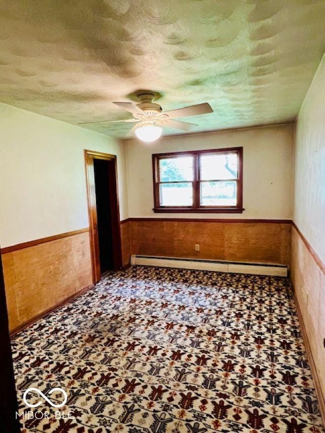 3824 Forest Ridge Dr, Fort Wayne, IN 46804 - unfurnished room with wainscoting, a baseboard heating unit, tile patterned floors, a ceiling fan, and a textured ceiling