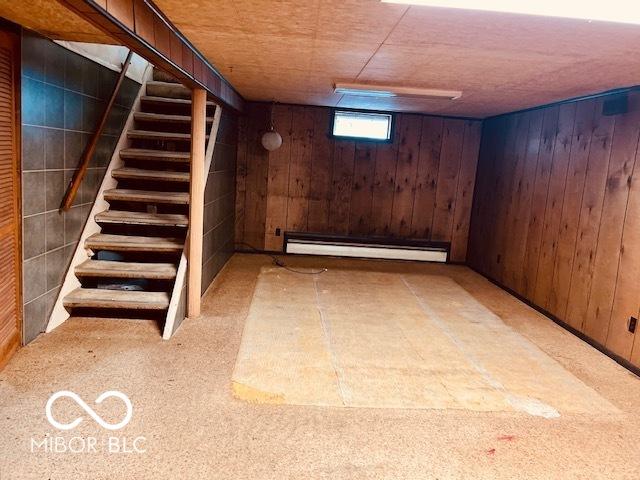 3824 Forest Ridge Dr, Fort Wayne, IN 46804 - below grade area featuring baseboard heating, wood walls, stairway, and carpet