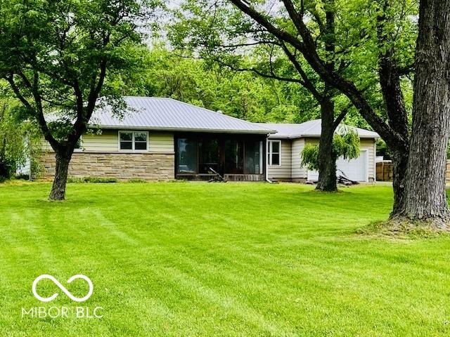 3824 Forest Ridge Dr, Fort Wayne, IN 46804 - rear view of house with a garage, a lawn, stone siding, and a sunroom