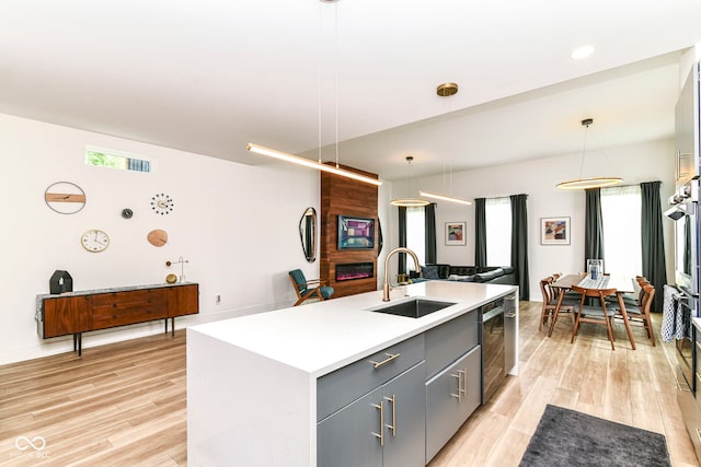 1620 W New York St, Indianapolis, IN 46222 - kitchen featuring a sink, gray cabinetry, light wood-style floors, open floor plan, and a center island with sink