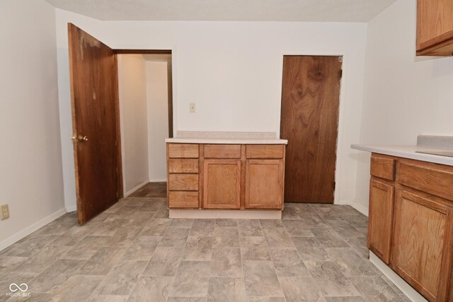 2622 Ethel Ave, Indianapolis, IN 46208 - kitchen with light countertops, brown cabinets, baseboards, and stone finish flooring