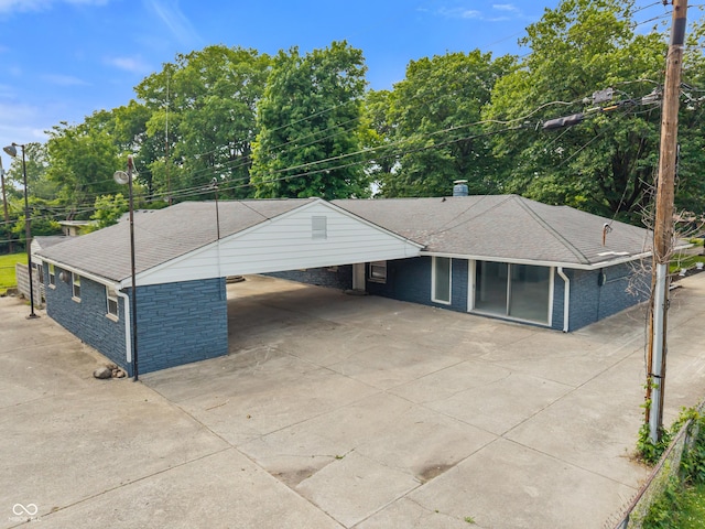 3735 Marrison Pl, Indianapolis, IN 46205 - view of front facade with driveway, a carport, a shingled roof, and view of scattered trees