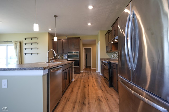 9018 E Gayle Dr, Morgantown, IN 46160 - kitchen with appliances with stainless steel finishes, tasteful backsplash, under cabinet range hood, dark countertops, and light wood-style flooring