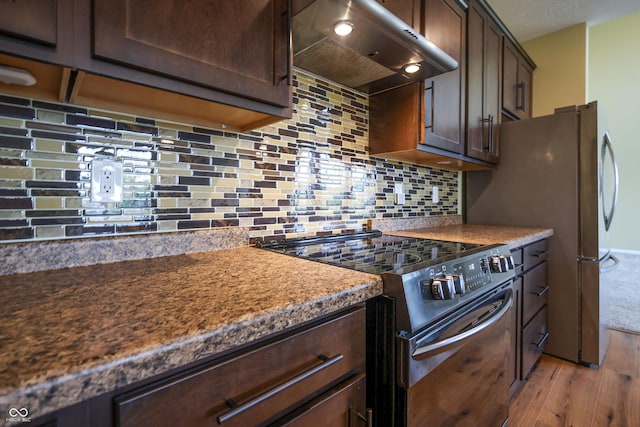 9018 E Gayle Dr, Morgantown, IN 46160 - kitchen with electric range, extractor fan, light wood-style floors, dark brown cabinets, and decorative backsplash