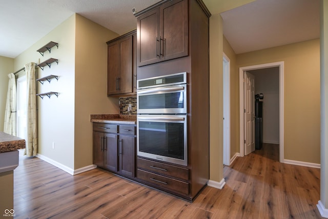 9018 E Gayle Dr, Morgantown, IN 46160 - kitchen featuring double oven, dark wood-style flooring, dark brown cabinets, decorative backsplash, and dark countertops