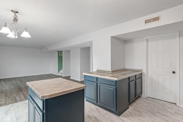 1408 Snead Cir, Avon, IN 46123 - kitchen featuring light countertops, hanging light fixtures, blue cabinets, a kitchen island, and open floor plan