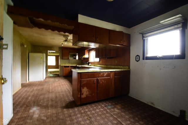 10577 Dalton Rd, Hagerstown, IN 47346 - kitchen with a peninsula, light countertops, a ceiling fan, wall chimney exhaust hood, and baseboards