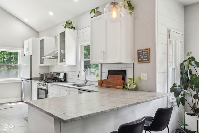 923 42nd St, Indianapolis, IN 46205 - kitchen with appliances with stainless steel finishes, white cabinetry, backsplash, a peninsula, and a kitchen bar