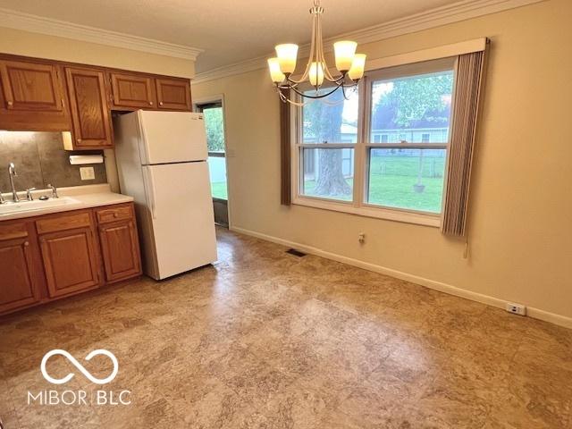 1834 Chandler Ln, Columbus, IN 47203 - kitchen with freestanding refrigerator, a sink, brown cabinetry, healthy amount of natural light, and crown molding