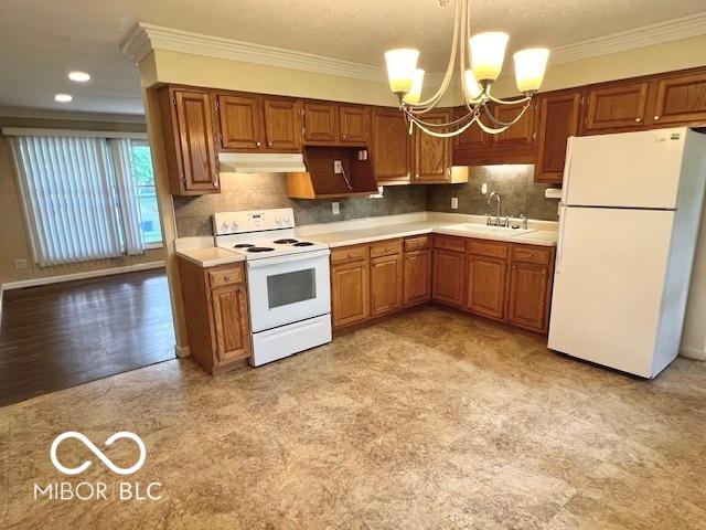 1834 Chandler Ln, Columbus, IN 47203 - kitchen with white appliances, a sink, under cabinet range hood, crown molding, and a chandelier