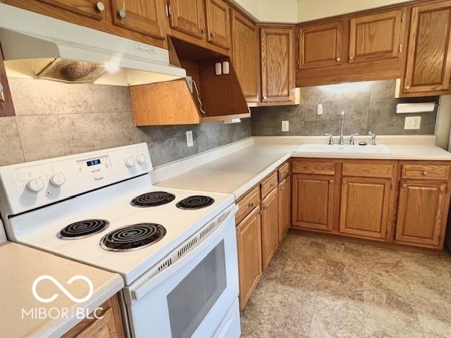 1834 Chandler Ln, Columbus, IN 47203 - kitchen featuring white electric stove, a sink, under cabinet range hood, brown cabinets, and light countertops
