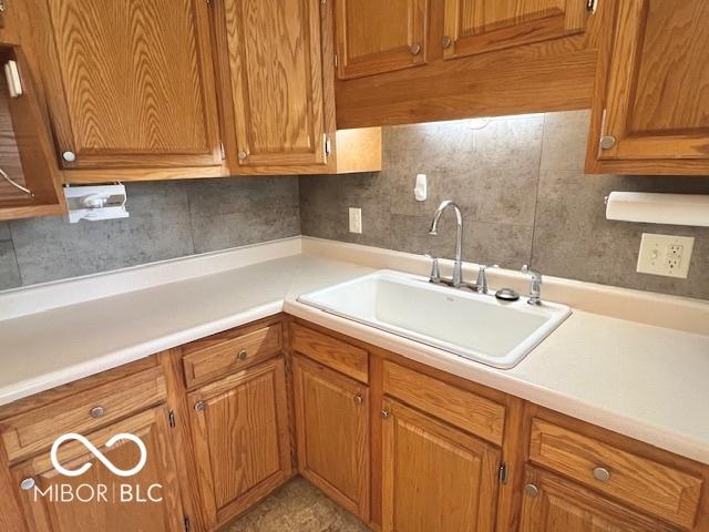 1834 Chandler Ln, Columbus, IN 47203 - kitchen featuring a sink, brown cabinets, light countertops, and backsplash