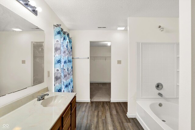 630 Harmony Way, Greenwood, IN 46143 - full bathroom with wood finished floors, vanity, a garden tub, a textured ceiling, and a spacious closet
