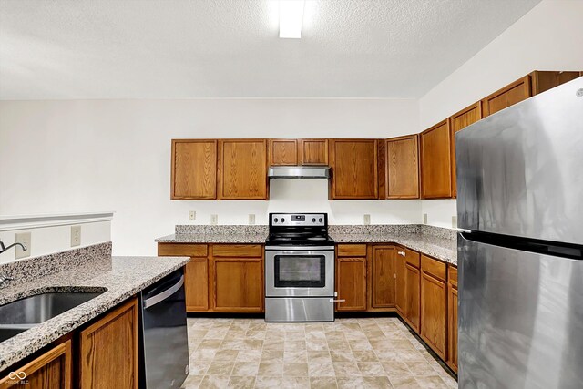 630 Harmony Way, Greenwood, IN 46143 - kitchen featuring stainless steel appliances, under cabinet range hood, a sink, brown cabinets, and a textured ceiling