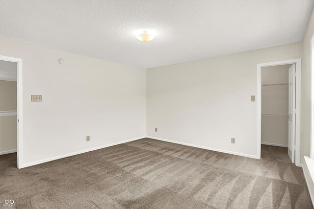 630 Harmony Way, Greenwood, IN 46143 - unfurnished bedroom with a spacious closet, carpet flooring, baseboards, a closet, and a textured ceiling