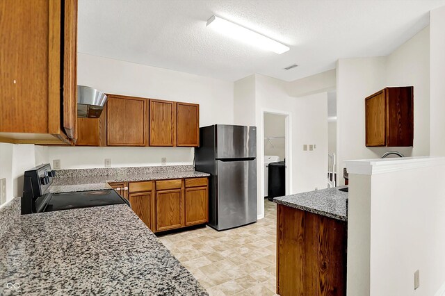 630 Harmony Way, Greenwood, IN 46143 - kitchen with freestanding refrigerator, black electric range, brown cabinets, washer / dryer, and a textured ceiling
