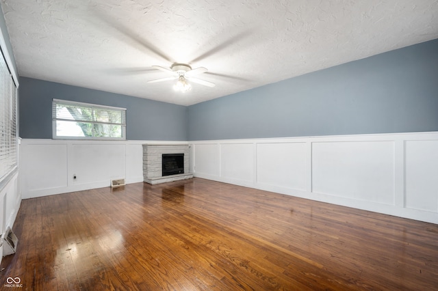 5092 S 50 W, Anderson, IN 46013 - unfurnished living room featuring a decorative wall, a ceiling fan, wood finished floors, a stone fireplace, and wainscoting