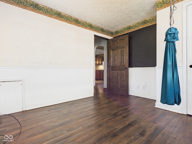 619 Belzer Dr, Anderson, IN 46011 - empty room with a wainscoted wall, arched walkways, wood finished floors, and a textured ceiling