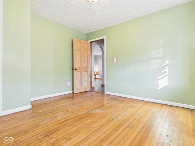 619 Belzer Dr, Anderson, IN 46011 - spare room with light wood-style floors, arched walkways, baseboards, and a textured ceiling