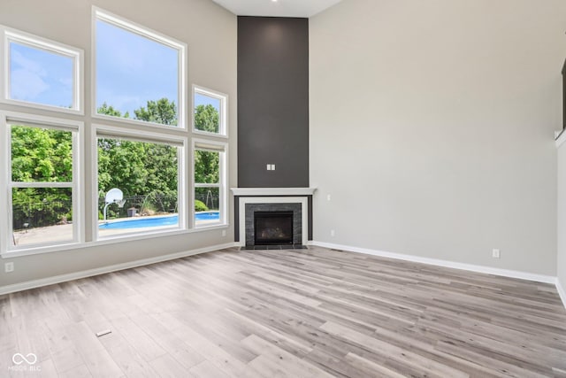644 Ridge Gate Dr, Brownsburg, IN 46112 - unfurnished living room with baseboards, a high ceiling, wood finished floors, and a fireplace with flush hearth