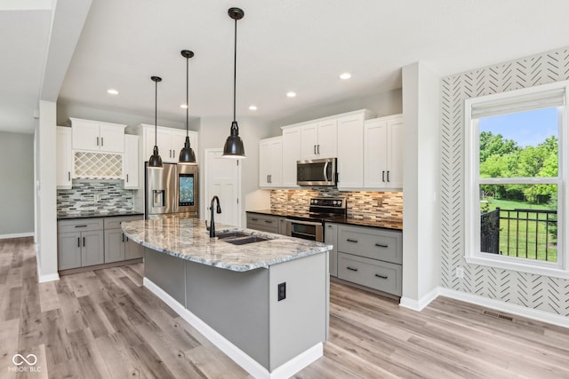 644 Ridge Gate Dr, Brownsburg, IN 46112 - kitchen with appliances with stainless steel finishes, baseboards, decorative backsplash, a sink, and a center island with sink